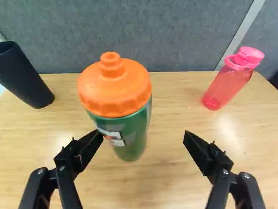 Wrist camera: the gripper closes on a green sports bottle with an orange cap standing on a wooden table.