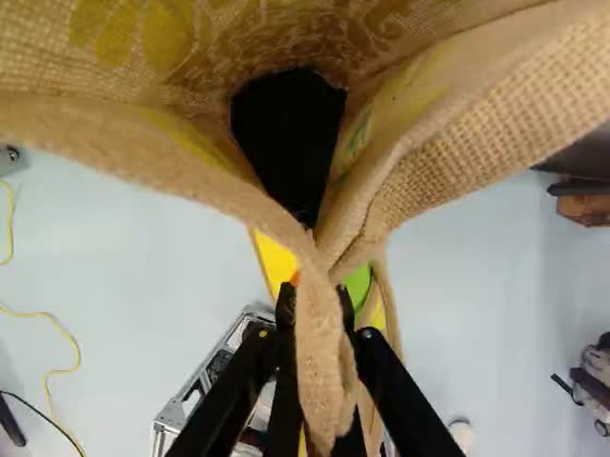 Wrist camera: the gripper closes on the folded handles of a woven jute bag.
